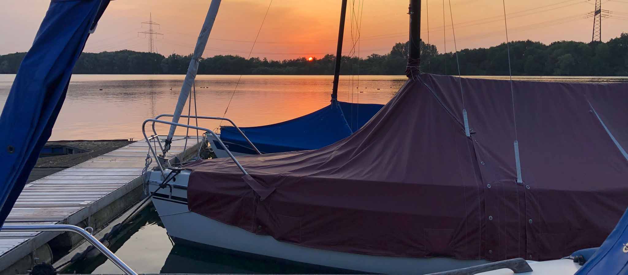 Sonnenuntergang auf Stegen vor Booten